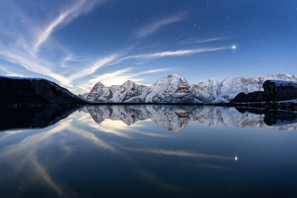 Cielo serale con stelle e nuvole sopra le cime innevate del Lago di Berna